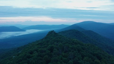 An aerial shot (dolly in) of Big Schloss, Great North Mountain and the Trout Run Valley at dawn in the summer, located on the Virginia/West Virginia Border within the George Washington National Forest