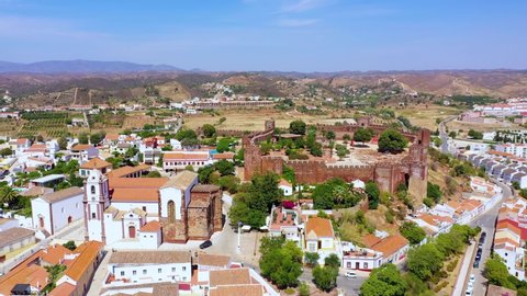 Aerial view away from the Cathedral and the castle of Silves, sunny day, in Faro, Algarve, Portugal - pull back, drone shot