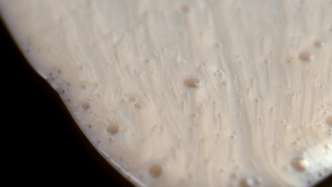 Beige Colored Cosmetic Liquid Flowing On Black Surface - macro, slow motion - Βίντεο στοκ