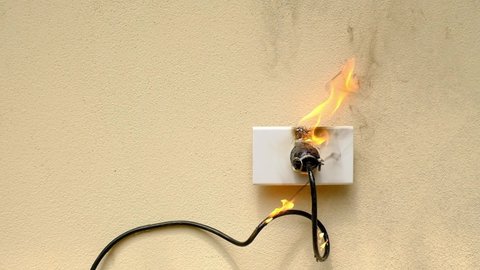 On fire electric wire plug peceptacle on the concrete wall exposed concrete background