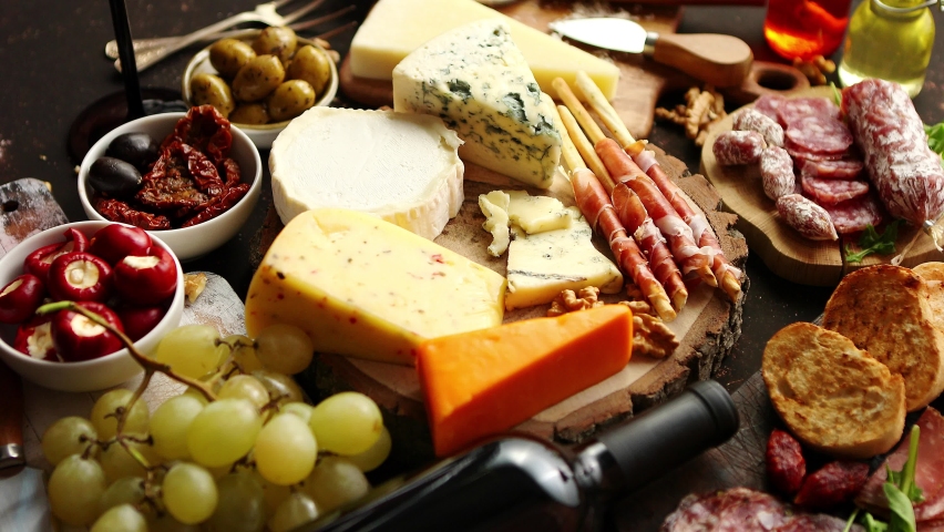 Huge assortment of various tasety spanish, french or italian apertizers. Cheese, meat, olives, stuffed peppers, bread, sticks. Placed on rusty dark background. View from above. | Shutterstock HD Video #1059970379