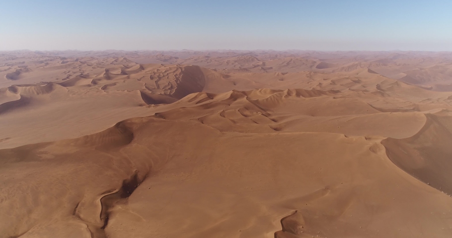 high attitude dolly in aerial view from the shape of sand dunes in dasht e lut or sahara desert, aerial shot from sand dunes