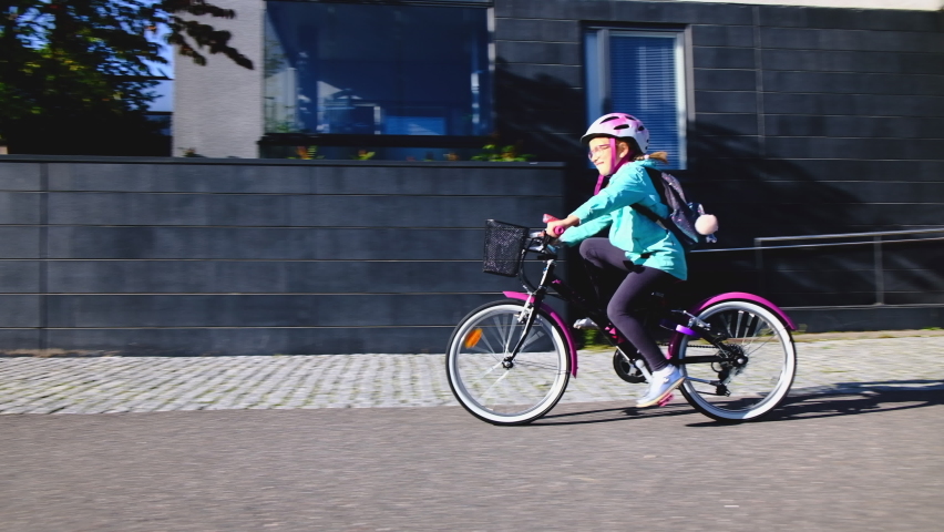 The girl rides the bicycle to school on a sunny morning. | Shutterstock HD Video #1059977003