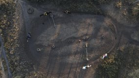 Five horsewomen ride by trot horseback in paddock in equestrian club. View from drone.
