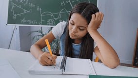 upset kid writing in notebook and throwing pen on table