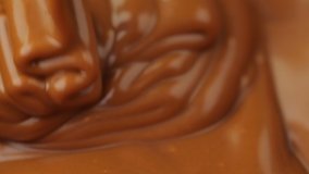 Caramel dripping thick strand. Motion of pouring melted dark chocolate.