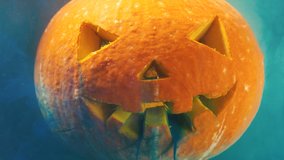 Yellow and blue paints cover orange Halloween pumpkin with cut face creating green colour in water extreme closeup