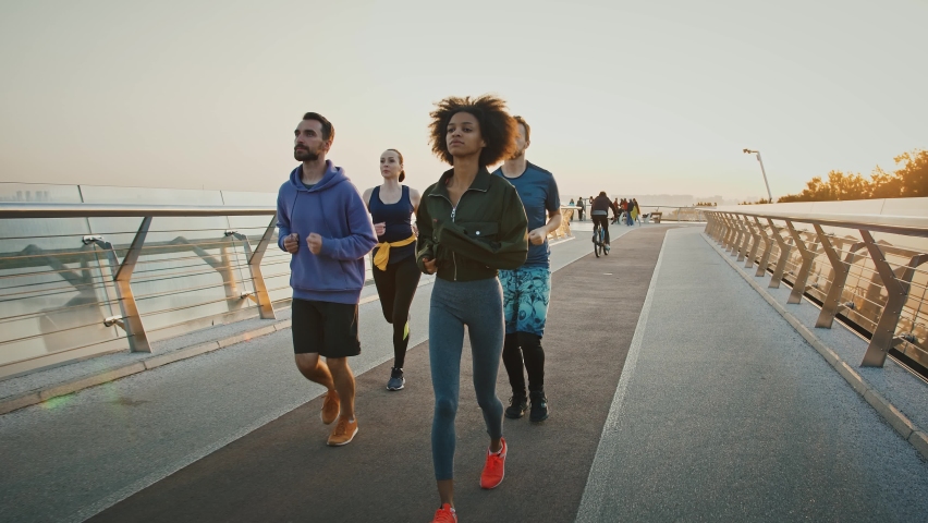 Morning run workout. Group of multiracial people jogging together on sport path in big city, slow motion Royalty-Free Stock Footage #1059992126