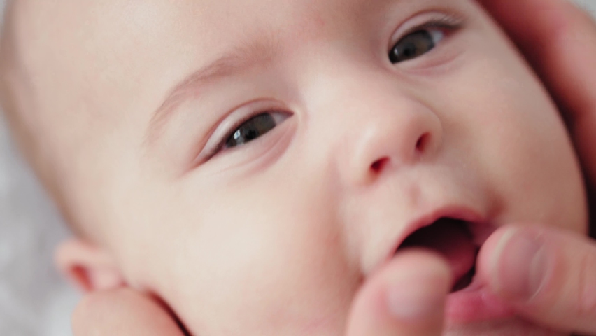 Medicine, pediatrics, dentistry, newborns concept - mom open baby mouth showing first milk baby tooth erupted from swollen gums. super close-up portrait of baby smiling with his mouth open with joying | Shutterstock HD Video #1059994106