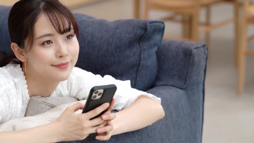 Young asian woman using a smart phone in the room. Royalty-Free Stock Footage #1059999650