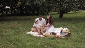 Mom, dad and their young son on a picnic in the park in the summer