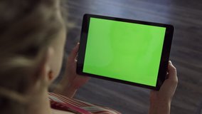 Woman holds tablet device in landscape orientation with blank green screen - Powered by Shutterstock - Get 15% off with code: PIKWIZARD15