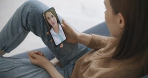 Female using online chat to talk with family therapist and checks possible symptoms during pandemic of coronavirus. Woman using medical app on smartphone consulting with doctor via video conference.