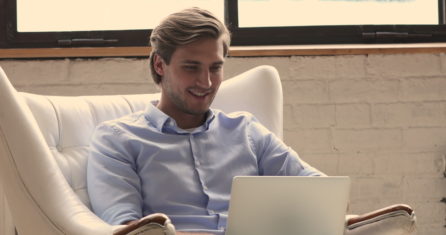 Carefree 30s guy sit in white leather comfy armchair use laptop spend free time buy or chat on-line, browse internet. Furnishing shop advertising of comfortable modern office or home furniture concept Royalty-Free Stock Footage #1060008368