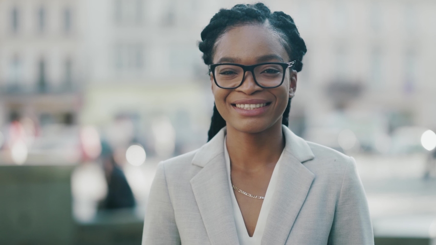 Nice portrait of beautiful african black young woman face smiling excitedly on busy street outdoors. Summertime. Attractive people. Businesswoman posing in the city. Royalty-Free Stock Footage #1060012682