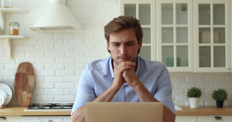 Thoughtful doubtful 30s young male student or writer sitting at table in kitchen in front of laptop search of inspiration, thinking over issue problem solution, create new fresh business ideas concept Royalty-Free Stock Footage #1060022387