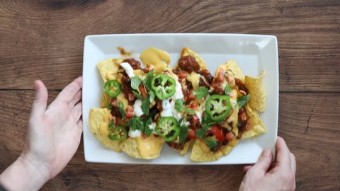 Serving a Plate of Nachos with Chili and Cheese