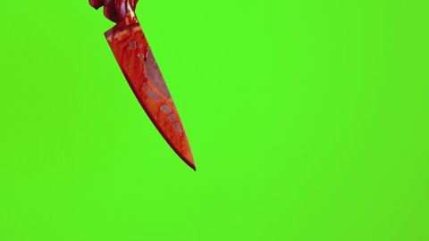 A womans hand with a knife in the blood. On a green background, blood drips from a womans downturned hand with a knife.