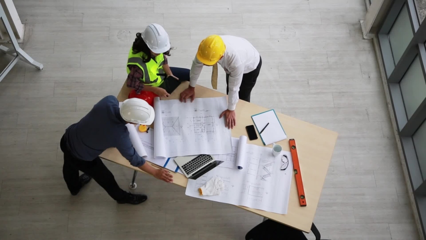Team of engineers and architects working, planing, measuring layout of building blueprints in construction site. top view | Shutterstock HD Video #1060034792