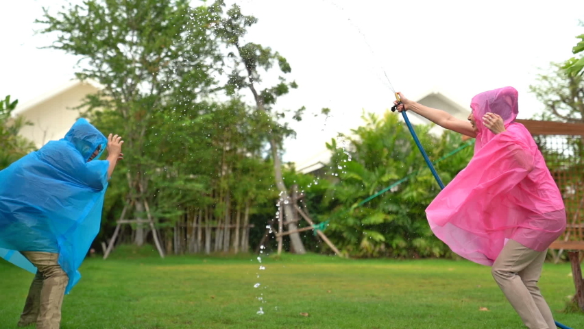 Happy Couple watering the plants In the home garden and enjoying the beautiful nature.