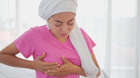 Asian woman with breast pain touching chest on white background, Unhealthy girl clutching chest, feeling acute pain and scared of heart attack, infarction or breast cancer symptoms.
