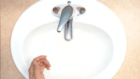 Aerial view of a man`s hands above a sink washing his hands with soap and warm water for over 20 seconds in order to limit the spread of viruses like Corona virus.