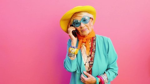Footage of a funny grandmother with fashionable look acting on colored backgrounds