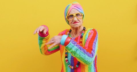 Footage of a funny grandmother with fashionable look acting on colored backgrounds