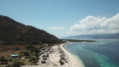A drone shot of a fisherman's village, located on a seashore of a small island next Flores, Indonesia. Clear, turquoise coloured water displaying coral reef. Solitude and calmness. Simple construction