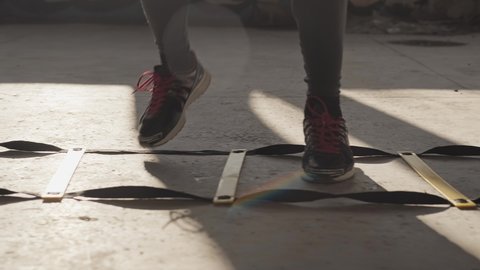 Boxer jumping on divided sections on floor. Close-up of sneakers. Athlete training in abandoned building while stepping. MMA fighter training legs. 4K, UHD
