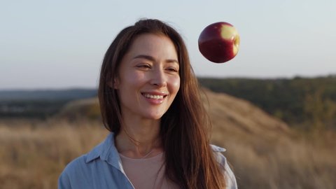 Beautiful young woman smiling holds an apple in her hand and also throws an apple