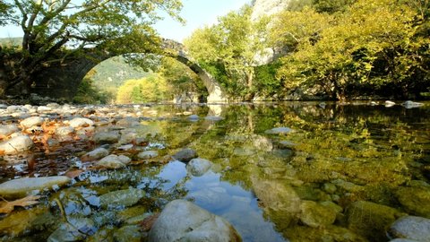 The fantastic Klidonia Ottoman bridge, above the peaceful Voidomatis river, in a beautiful morning light and reflections, a 4K video, Zagori, Greece.