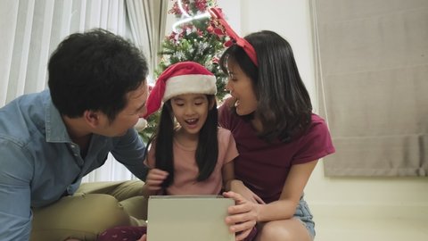 Happy family time and relationship, Asian family having small christmas party together at home. Young parents with little child open xmas present box with happiness then looking camera with smile.