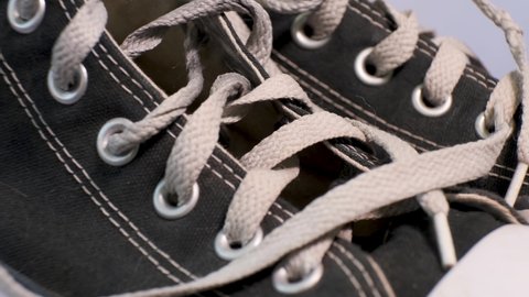 Close-up of rotating pair of black used sneakers Converse with white laces. Sport shoes, youth fashion concept.