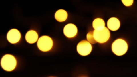 Abstract bokeh background in motion. shining, blurred golden particles, lights. bright bokeh from garlands on dark background. New year or Christmas festive backdrop.