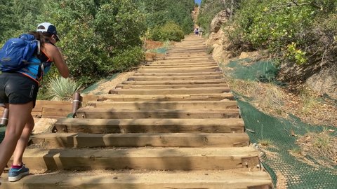 Manitou Springs, Colorado - September 19, 2020: The old railroad ties that make up the Manitou Incline hike in Colorado. Woman hiker climbs the stairs