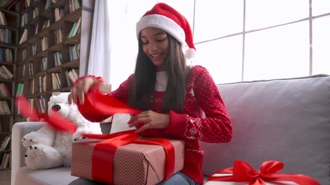 Happy indian latin kid girl opening xmas gift video calling family, webcam view. Smiling hispanic child talking to camera virtual meeting social distance friend celebrating Christmas New Year at home.