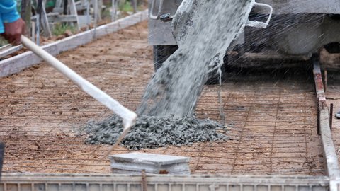Pouring concrete mix on concreting formwork on road in construcktion site