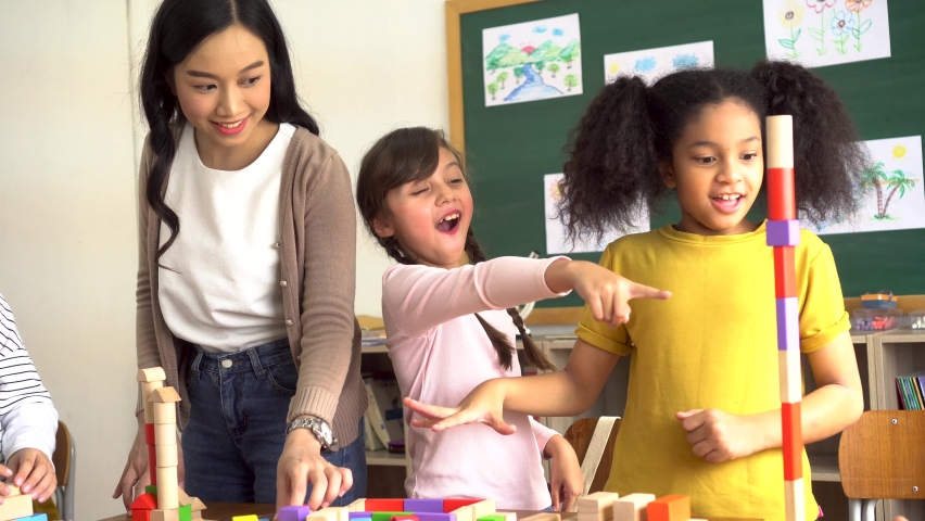 Group of multiethnic school friends using toy blocks in classroom, education, learning, teamwork. Children playing with wooden blocks in classroom Royalty-Free Stock Footage #1060074767
