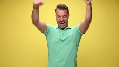 casual guy with his arms crossed is looking at the camera and smiling, celebrating succes and being fired up on yellow background