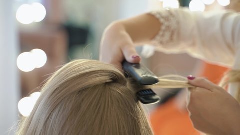 professional hairdresser gives volume to hair in beauty salon