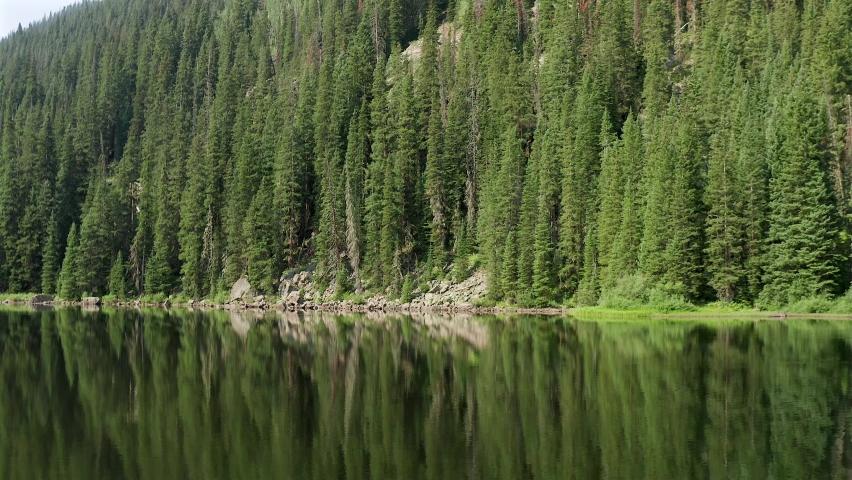Low Aerial drone footage over a glassy Beaver Lake, in Beaver creek, Colorado