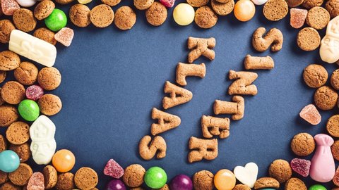 Stop motion animation. Sinterklaas is coming soon, 4K. Dutch holiday St Nicholas day concept with letters, traditional sweets and cookies, kruidnoten on blue background. Top view. Vertical orientation