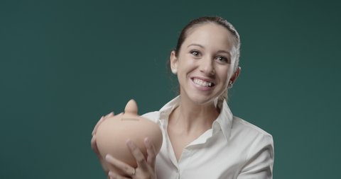 Young businesswoman holding a clay money box and smiling, saving money and investments concept