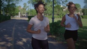 Two young cute women caucasian and hispanic jogging at the park to keep fit - Couple of female mixed race friends running together in the morning for their healthy
