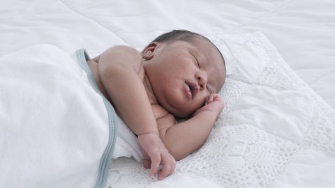 Close up of Mixed race black boy Ethnicity Thai-Nigeria. Newborn baby sleeping on the bed in home and nature sunlight