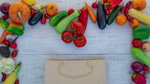 Vegetables in a brown paper bag on a white wood background. Environmentally friendly packaging concept, stop motion animation, 4K