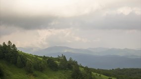 Timelapse. Running gray cloudy clouds on the background of hills in the Kusatsu Onsen area
