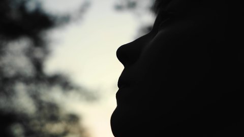 Silhouette of a boy's face against the background of the evening sky. The boy has a thoughtful look.