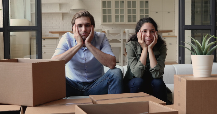 Tired couple sit on sofa surrounded by heap of big carton boxes look at each other feels upset due long run house remodeling, renovations, repairs. physical exhaustion after move out from flat concept Royalty-Free Stock Footage #1060104266